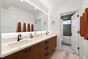 Bathroom featuring double vanity, shower / tub combo with curtain, recessed lighting, and light tile patterned flooring