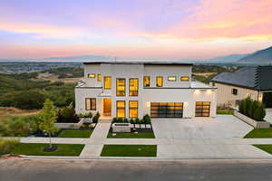 Modern home with concrete driveway, stucco siding, a lawn, and a mountain view
