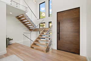 Entrance foyer with stairs, a high ceiling, and light wood-style floors