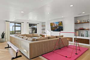Living room with light wood-type flooring, recessed lighting, and built in features