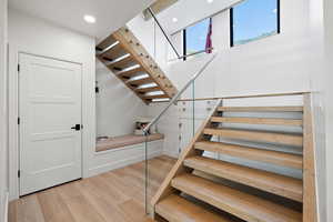 Staircase with wood finished floors and recessed lighting
