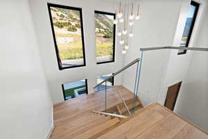 Staircase with plenty of natural light, a chandelier, and wood finished floors