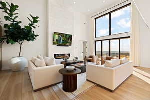Living area featuring a high ceiling, a large fireplace, and light wood-style flooring