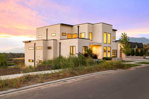 Modern home with stucco siding, a mountain view, a garage, and driveway