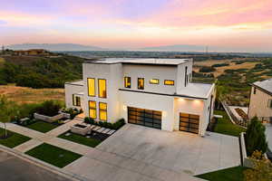 Contemporary home featuring driveway, a front lawn, a mountain view, and stucco siding