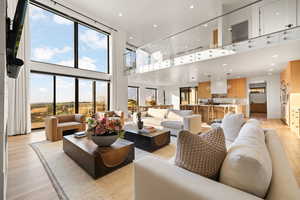 Living area featuring a towering ceiling, light wood-style flooring, and recessed lighting