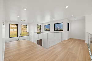 Hall with light wood finished floors and recessed lighting