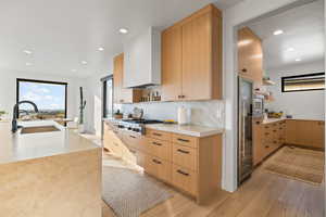 Kitchen featuring open shelves, light brown cabinetry, light wood-style floors, light stone counters, and recessed lighting