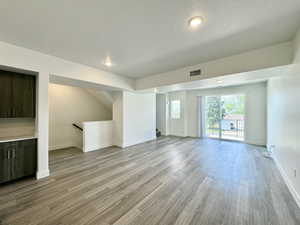 Unfurnished living room featuring a textured ceiling, light wood-style floors, and recessed lighting