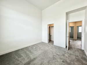 Unfurnished bedroom featuring a walk in closet, carpet flooring, and a high ceiling