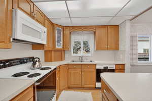 Kitchen with white appliances, light countertops, brown cabinets, and light wood-type flooring