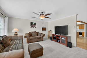 Living room featuring light carpet, Crown molding, and a ceiling fan