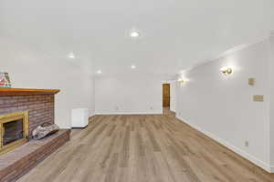 Downstairs family room with a fireplace, crown molding, light LPV flooring, and recessed lighting
