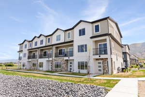 View of front of house with stone siding, a residential view, a balcony, and a mountain view