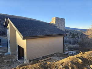 View of home's exterior with roof with shingles and a chimney