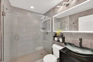 Full bath with vanity, a stall shower, and tile walls