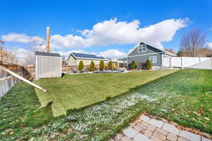 Fenced backyard with a storage unit and a patio area