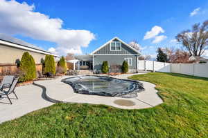 Rear view of house with board and batten siding, a patio area, and a fenced backyard