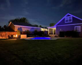 Yard at night featuring a patio, a yard, an outdoor pool, and an outdoor fire pit