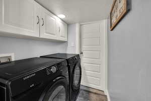 Washroom with a textured ceiling, separate washer and dryer, and cabinet space