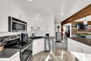 Kitchen featuring appliances with stainless steel finishes, white cabinetry, light tile patterned floors, recessed lighting, and decorative backsplash