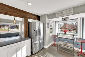 Kitchen featuring stainless steel fridge, plenty of natural light, white cabinetry, pendant lighting, and recessed lighting
