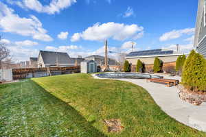Fenced backyard featuring a shed and a patio area
