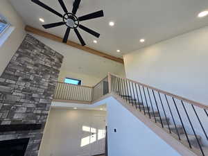 Staircase featuring recessed lighting, a towering ceiling, a stone fireplace, and ceiling fan