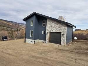 View of home's exterior featuring a chimney, a garage, and stone siding