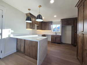 Kitchen featuring light stone countertops, dark wood-style flooring, hanging light fixtures, recessed lighting, and a peninsula