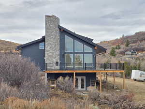 Back of property featuring a deck with mountain view, a chimney, and french doors