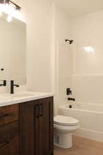 Bathroom with vanity, light wood-style flooring, and shower / washtub combination