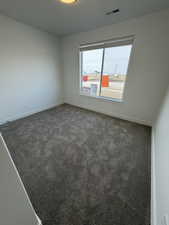 Empty room with dark colored carpet and baseboards