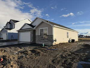 View of front of house with stone siding, an attached garage, and driveway