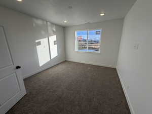 Spare room featuring dark colored carpet and recessed lighting
