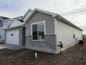 View of home's exterior featuring a garage, stone siding, and driveway