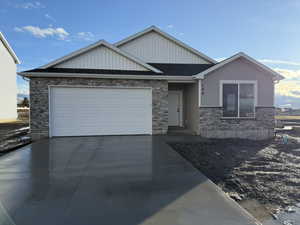 View of front of property featuring stone siding, concrete driveway, a garage, and board and batten siding