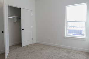 Unfurnished bedroom with light carpet and a closet