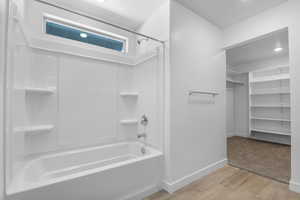 Bathroom featuring a spacious closet, shower / tub combination, and light wood-type flooring
