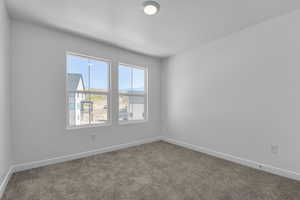 Carpeted empty room with a textured ceiling and baseboards