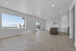 Kitchen with open floor plan, a center island with sink, light wood finished floors, recessed lighting, and a mountain view