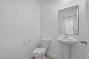 Half bath featuring baseboards and wood finished floors