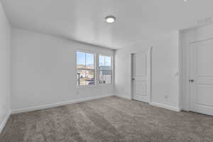 Unfurnished bedroom with a textured ceiling, light colored carpet, and a mountain view