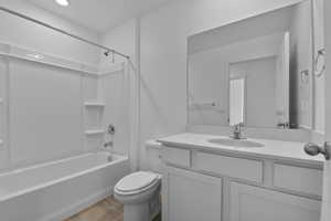 Bathroom featuring tub / shower combination, vanity, and light wood-style flooring