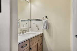 Half bathroom with decorative backsplash and vanity