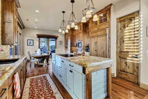 Kitchen featuring a kitchen island, recessed lighting, dark wood-style floors, glass insert cabinets, and decorative light fixtures