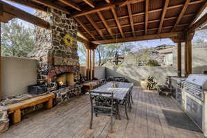Deck featuring outdoor dining space, exterior kitchen, and an outdoor stone fireplace