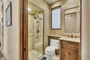 Full bath featuring vanity, a shower stall, and tile walls