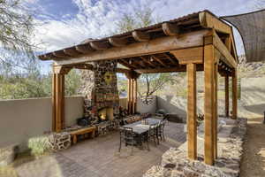 Fenced backyard featuring an outdoor stone fireplace, outdoor dining space, and a patio area