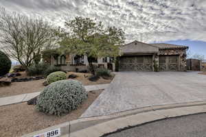 View of front of house with a garage, driveway, and stone siding